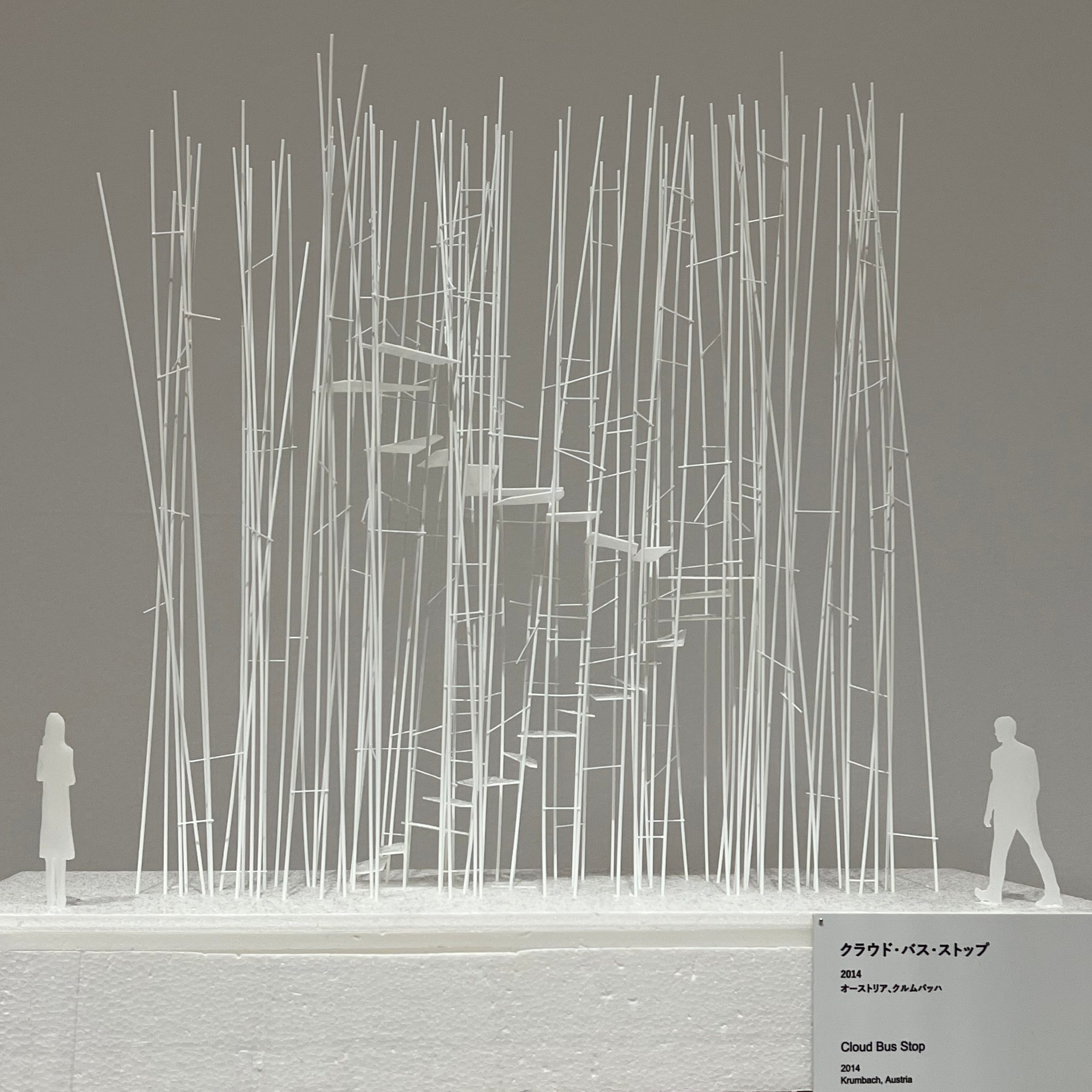 A white sculptural scale model of Sou Fujimoto's Cloud Bus Stop, 2014, Krumbach, Austria, with delicate vertical timber dowels and a spiral staircase form, on display at the exhibition.
