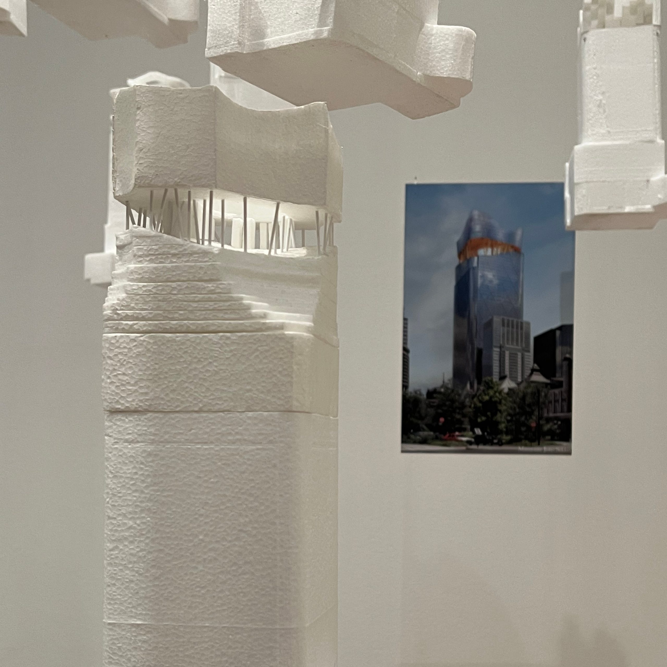 A white scale model of Sou Fujimoto's design for the Tokyo Torch Tower, displayed beside a reference photo of the tower